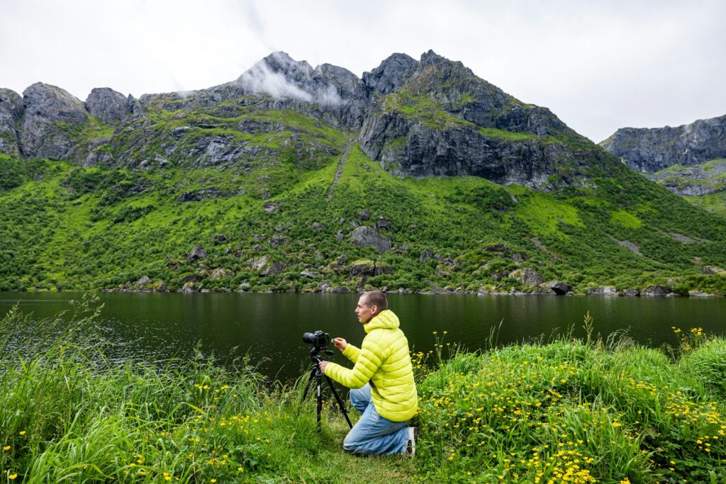 Man with camera near lake and mountains